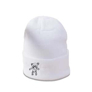 Détail du bonnet en tricot blanc avec une petite broderie d'ours noir de dessin animé