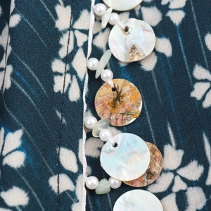 Detailed macro view of beaded embellishments with shells, pearls, and stones on printed fabric