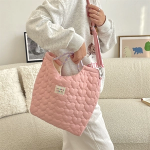 Détail d'un sac matelassé rose à motifs de cœur avec poignée tissée sur le modèle