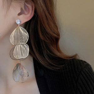 Detail of layered gold hollow leaf tassel earrings with clear crystal stud for women