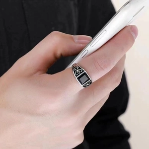 Retro silver men's ring with black square gemstone shown on hand while holding a phone