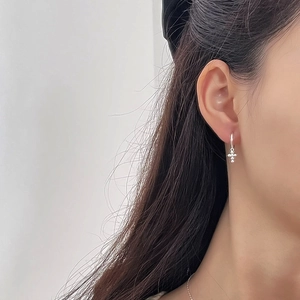 Close-up of S925 sterling silver minimalist cross hoop earrings worn by a model