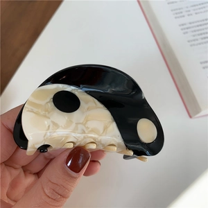 Detail of yin yang pattern on black and white acetate hair claw clip held in hand