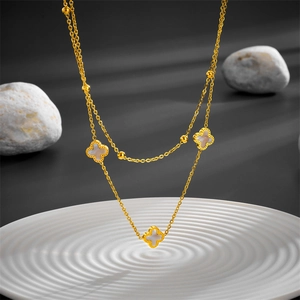 Close-up detail of a double-layered stainless steel clover necklace in gold finish
