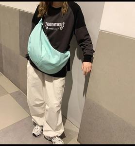 Street style shot of light blue nylon crossbody dumpling bag worn by a model