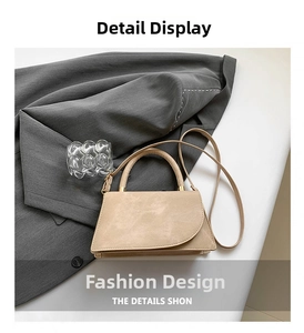 Detail showing beige suede textured handbag on grey blazer with curved flap and strap