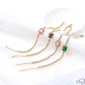 Elegante goldene Zirkonia-Armbänder mit bunten rechteckigen Steinen auf weißem Webpelz