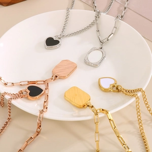 Detail of square shell and heart pendants on gold and silver layered necklaces in white dish