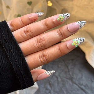 Detail of almond press-on nails with zebra stripes, polka dots, and floral 3D charms