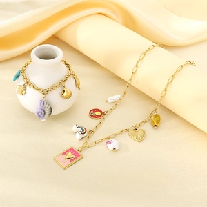 Détail du collier et du bracelet dorés avec breloques arc-en-ciel et fleurs sur satin