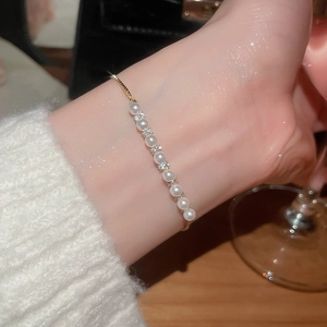 Detail of elegant gold bracelet with ten white pearls and sparkling zircon accents