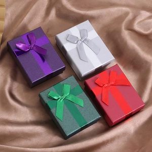 Detail of luxury jewelry gift boxes with satin bows on brown silk fabric background