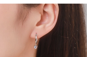 Close-up of S925 silver hoop earring with iridescent heart-shaped moonstone on model