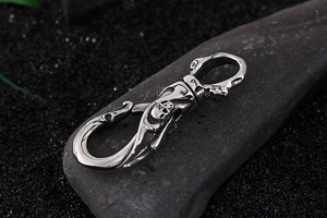 Detail of silver stainless steel skull keychain hook on dark natural stone background
