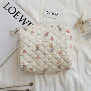 Détail macro de la trousse de maquillage en coton matelassé avec imprimés lapin et étiquette