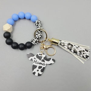 Detail of blue and cow print silicone bead bracelet with Mama cow head charm and tassel