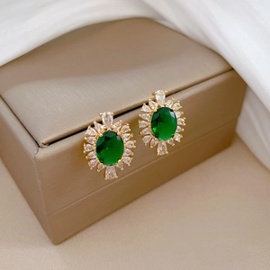 Macro shot of gold-plated earrings with emerald green stone and marquise crystals