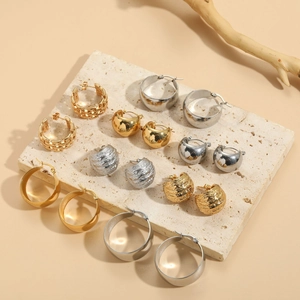 Macro shot of assorted gold and silver geometric hoop earrings on a stone tray