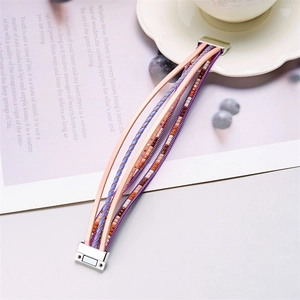 Détail du bracelet multicouche en cuir rose et violet avec perles et fermoir magnétique