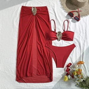 Detailed flat lay of red three-piece bikini set with golden shell buckles and sarong