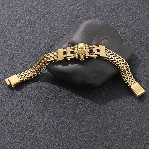 Gothic punk skull bracelet in polished gold finish displayed on black stones