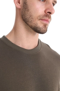 Close-up of olive green crew neck sweatshirt showing ribbed neckline and cotton fabric texture