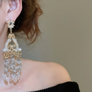 Close-up of crystal tassel drop earrings with pearls and gold-tone intricate metalwork