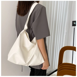 Professional model carrying a large off-white tote bag against a neutral backdrop