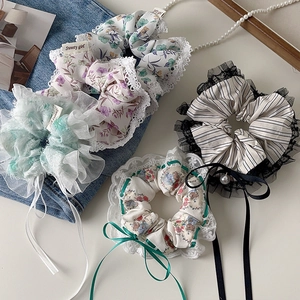 Close-up of floral scrunchies with lace trim, bows, and pearl charms in various patterns