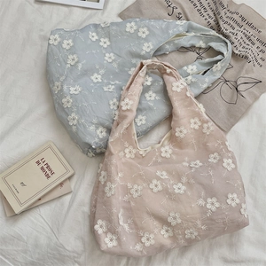 Detail of floral embroidery on soft fabric shoulder bags in light blue and pink tones