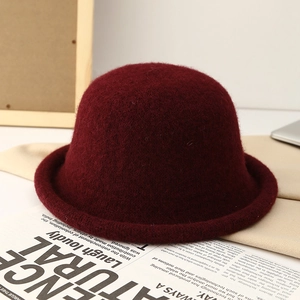 Close-up of a burgundy wool bucket hat with rolled edge detail on art newspaper