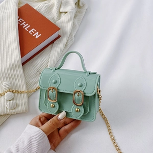 Mint green mini satchel bag with gold chain strap on white ribbed fabric background