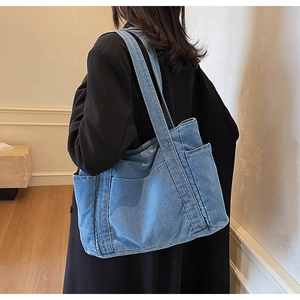 Detail of blue denim tote bag side pocket and vertical stitching on durable canvas