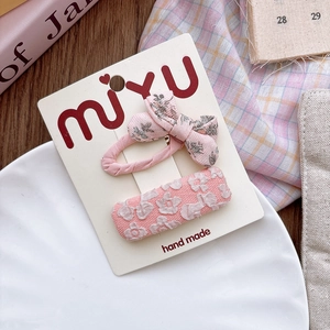 Detail of pink floral fabric bow hair clip set for girls on a gift card display