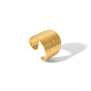 Close-up of wide gold cuff bracelet featuring horizontal textured lines and polished finish