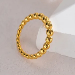 Minimalist gold beaded ball ring made of titanium steel on white stone display base