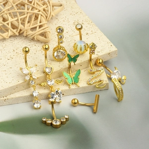 Detail of gold navel rings with butterfly and snake charms featuring zircon stones