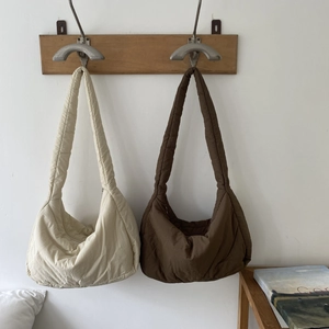 Detail of off-white and dark brown quilted puffer tote bags hanging on wooden hooks