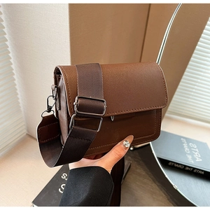 Detail of vintage brown crossbody bag featuring wide canvas strap and metal buckle