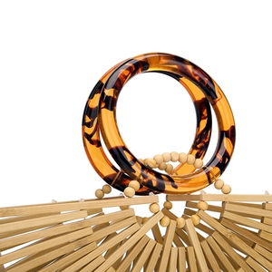 Detail of bamboo woven bag featuring acrylic handles with tortoise shell pattern