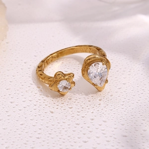 Macro shot of gold-plated open ring with teardrop zircon and textured surface