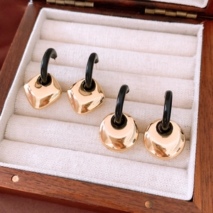Detail of luxury geometric gold finish earring set presented in a wooden jewelry box