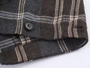 Nahaufnahme von braunem Karostoff und einem schwarzen Knopf mit vier Löchern am Kleid