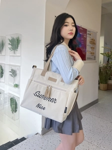 Detail of off-white canvas tote bag featuring black Summer Nice embroidery and side pocket