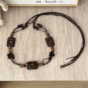 Detail of bohemian braided waist belt with heart wood charms and gold rose metal accents