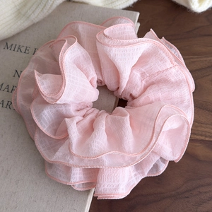 Detailed view of large pink tiered ruffle scrunchie with textured sheer fabric