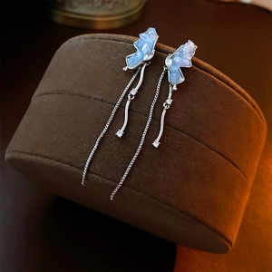 Macro shot of blue crystal butterfly earrings with silver tassels on brown velvet
