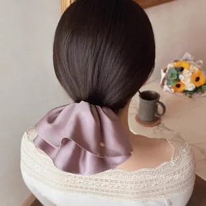 Detail of elegant satin scrunchie in dusty pink featuring a stylish gold metal button