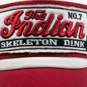 Macro shot of 3D embroidery with The Indian and Skeleton Dink text on a baseball cap