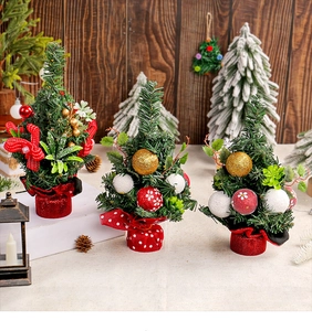Detail of mini Christmas trees with red bows and ornaments on rustic wooden tabletop